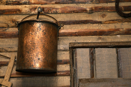 谷仓内的木墙上的旧铜桶图片