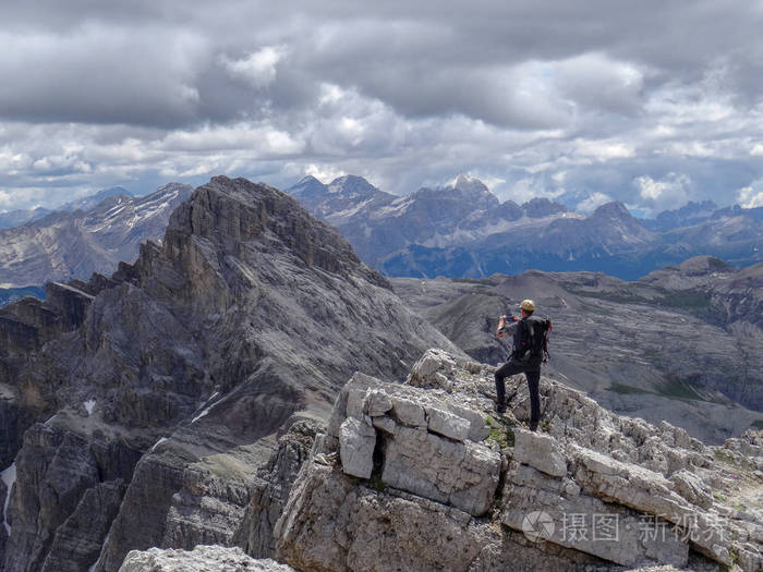徒步旅行者站在岩石上. 看着远处美丽的高山岩石.