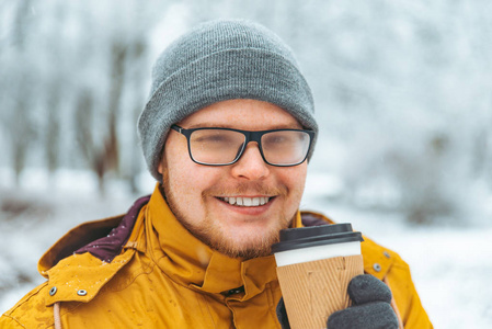 在下雪的冬天，男人喝咖啡去外面。 眼镜是雾状的。 特写肖像