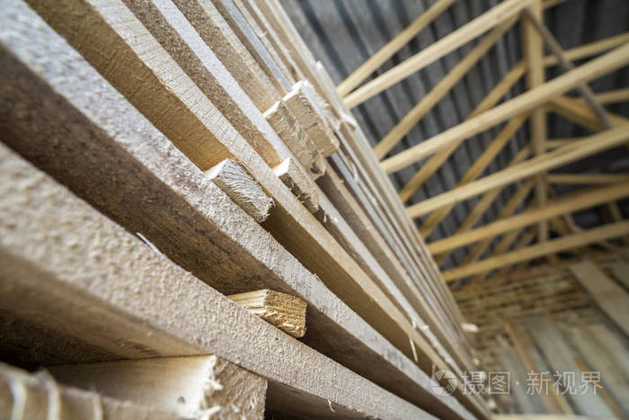 透视图整齐堆放的长堆自然凹凸不平的粗糙木板在阁楼房间内正在施工。 木工用工业木材建筑木材材料用于建筑。