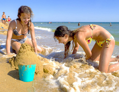 两个十几岁的妹妹在热带海滩做沙堡