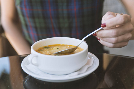 s hand with the spoon while eating soup in the restaurant