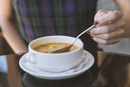 s hand with the spoon while eating soup in the restaurant
