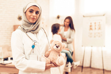 自信的穆斯林女医生抱着熊. 儿科医生的孩子. 医院概念. 健康的概 ..