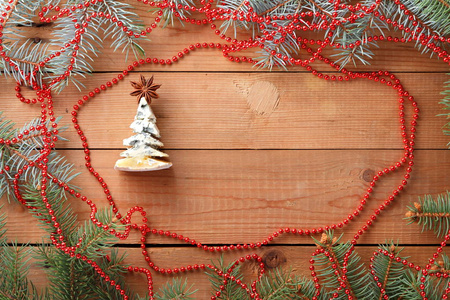 圣诞树由奶酪制成，木板上有红色装饰。 木制背景上的云杉枝。 由奶酪和八角制成的杉树。 节日图案顶部