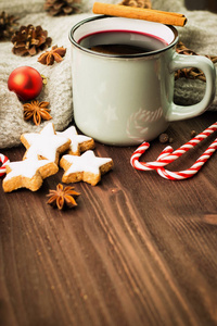 冬季和新年主题。 圣诞热蒸杯闪烁的葡萄酒与香料肉桂八角曲奇，形状明星红色糖果，杉果，胡椒和灰色围巾在木制背景。 复制文本空间。