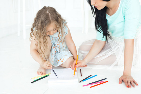 年轻的母亲和她的小女儿一起玩。 一家人用五颜六色的铅笔