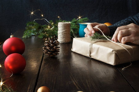男性手在木桌上包装礼品盒。 乡村圣诞背景。 包装背景