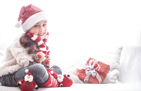 带圣诞礼物的小可爱女孩，穿着圣诞老人服装，沙发上，圣诞节和新年概念