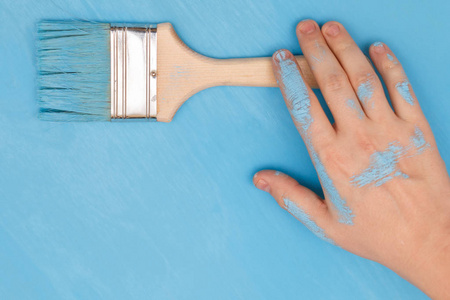 一只用油漆覆盖的雄手，手里拿着油漆刷在木棒上