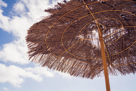 海滩风景。 竹苇草滩伞在阳光明媚的日子在沙滩上。 假期概念。