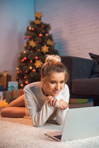 圣诞节的时候，一个年轻的金发女人正用笔记本电脑躺在地上