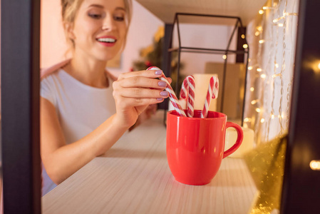在圣诞节的时候，带着微笑的金发女郎把糖果罐头放进红色的杯子里
