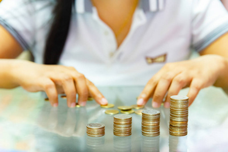省钱的女人把硬币堆成越来越多的柱子。