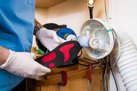 s hand of an employee urges an orthopedic insole on a machine to