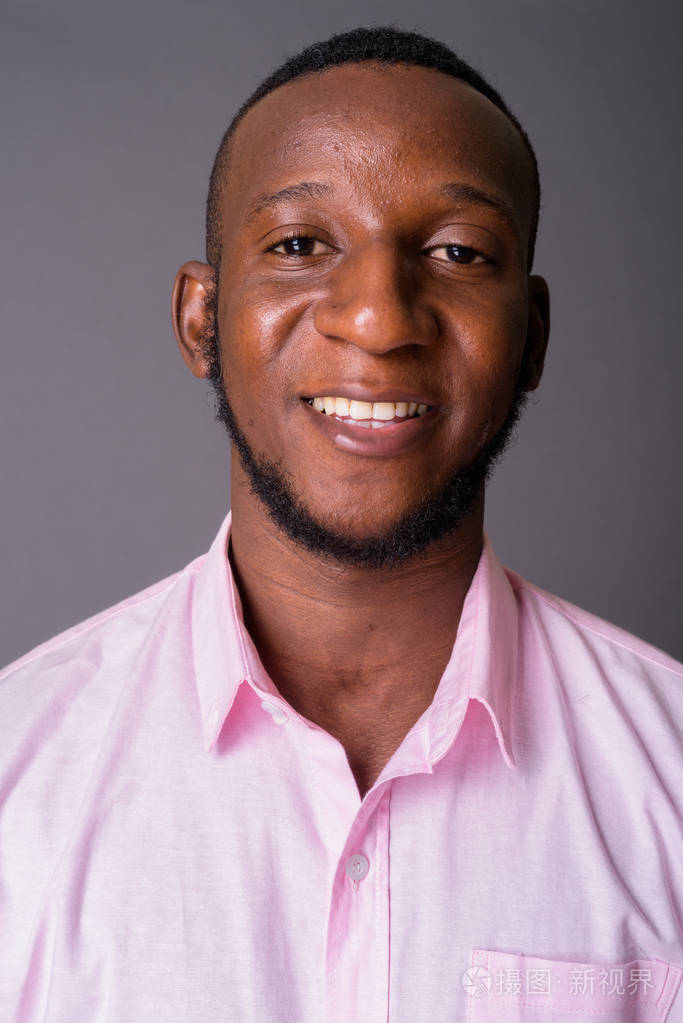 年轻英俊的非洲男人短发对灰色的背流