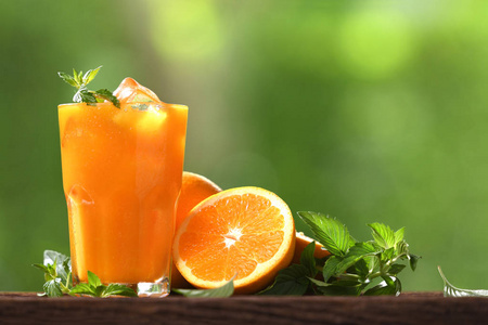 玻璃中的新鲜橙汁，木材上有橙片，自然背景