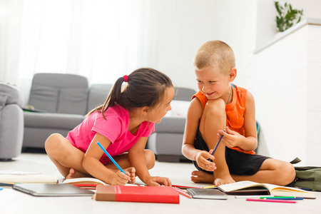有学龄前男孩的小女孩在家地板上学习