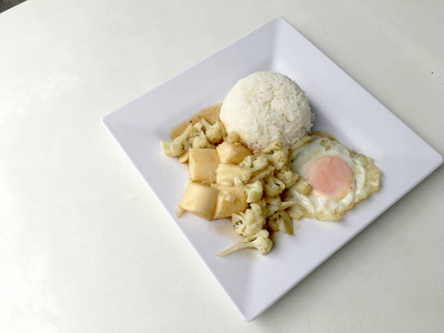 炒豆腐在中国风格的炒豆腐与肉汁酱，炒豆腐与菜花和泰国风格的炒鸡蛋在白色的盘子背景。 素食健康食品。