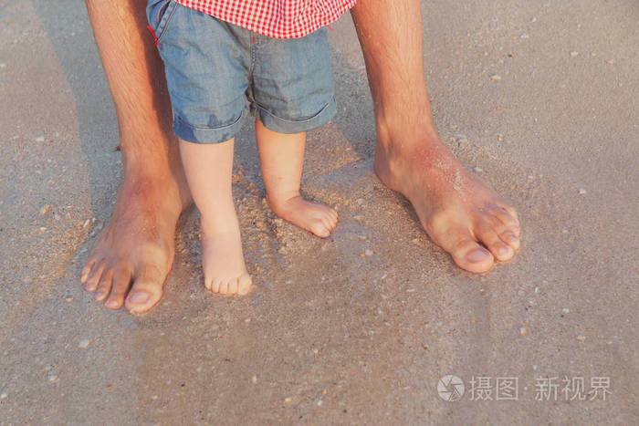 赤脚的父亲和他的小女儿或儿子呆在海边的沙子里. 旅行和假期的概念.
