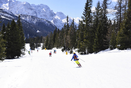 阿尔卑斯山的山峰覆盖着雪。 在阳光明媚的冬日，滑雪山坡上挤满了滑雪者