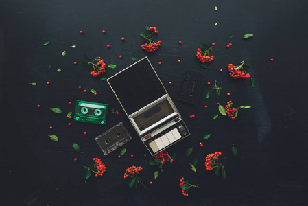 平躺音乐，音频盒和播放器怀旧形象，复古技术从80年代和90年代与野生浆果水果装饰的顶部视图。