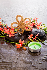 橙红色的松花，黑色的按摩石，绿色的茶色蜡烛和水滴在潮湿的灰色石板背景上的Burlap花形状