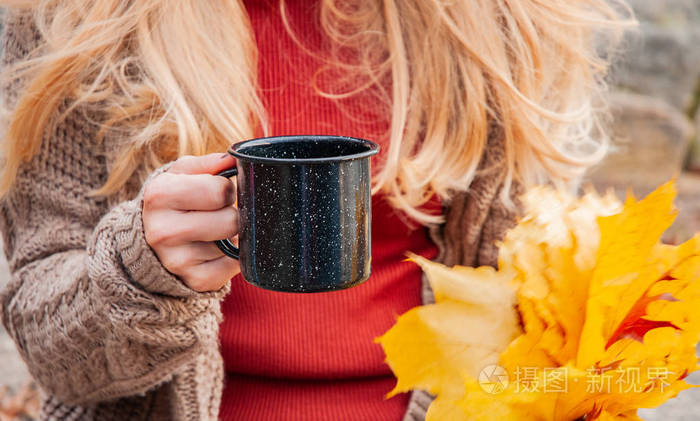 女人在户外手里拿着一杯咖啡. 美丽的女人在秋天公园喝咖啡.