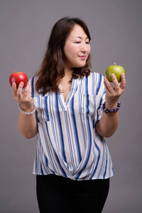 拿着苹果果实的成熟美丽的亚洲女商人