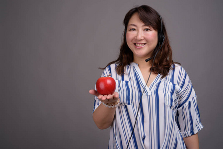 成熟的亚洲呼叫中心代表妇女拿着苹果