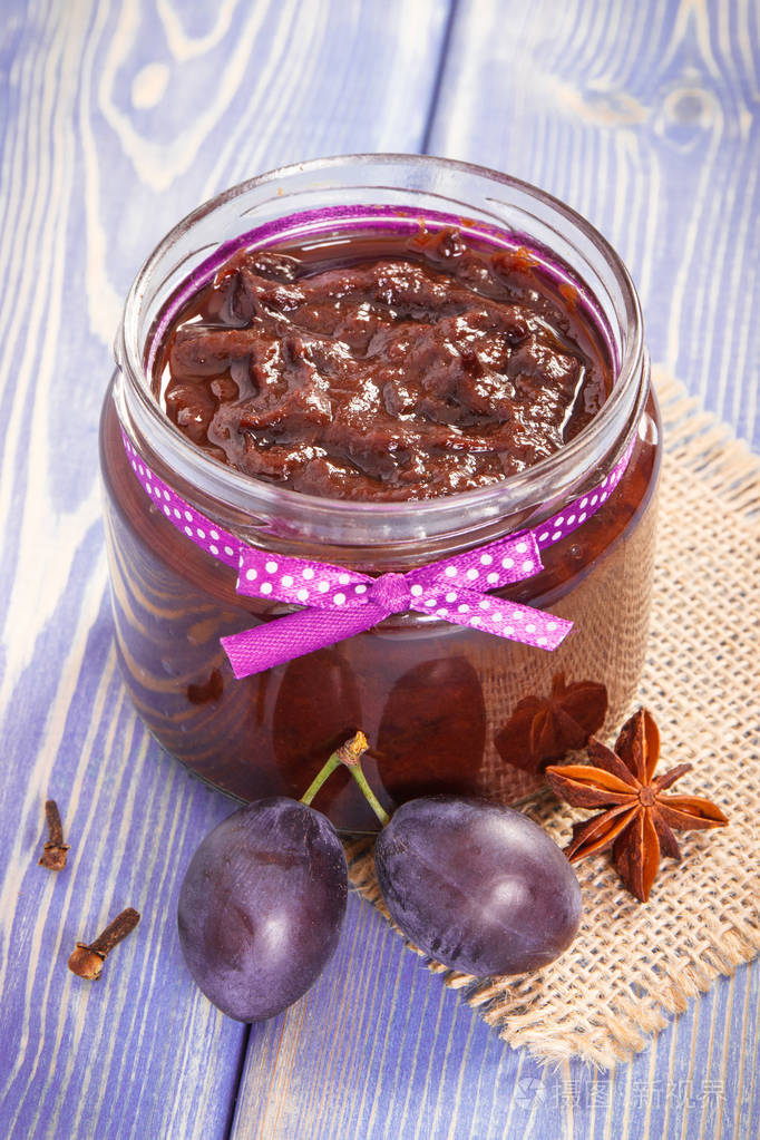新鲜自制的李子果酱或果酱在罐子里,水果和香料在木板上,健康的甜点