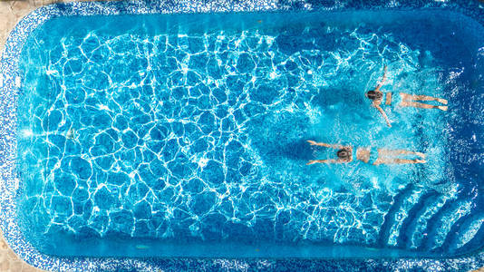 活跃的女孩游泳池，水，空中无人机，从上面的儿童游泳，孩子们玩得开心，热带家庭度假度假度假胜地的概念。