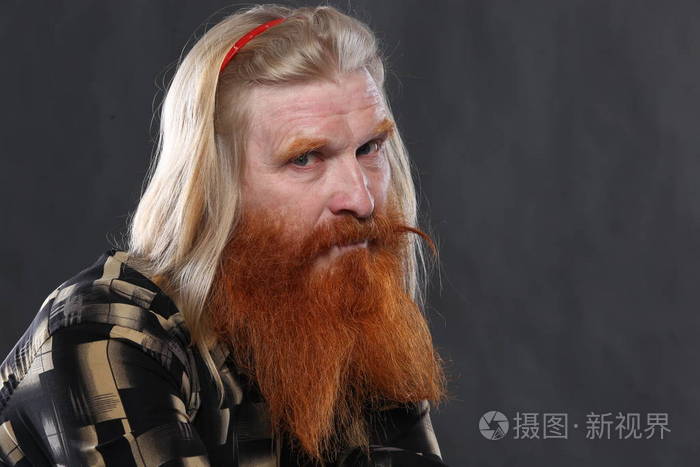 一位留着红胡子和胡子的成年男子在黑暗背景工作室的肖像