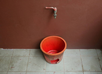 斗破仙穹脏地板上的破桶和棕色墙壁上的水龙头漏水的概念照片