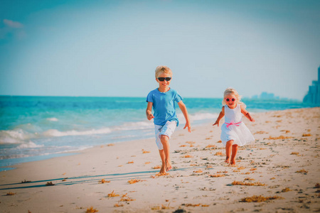 小男孩和女孩跑在海滩上玩