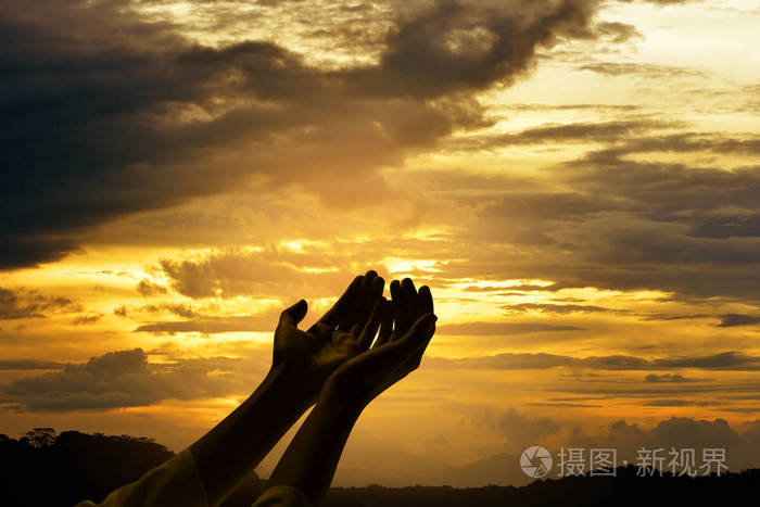 双手张开手掌在日出背景下向上帝祈祷