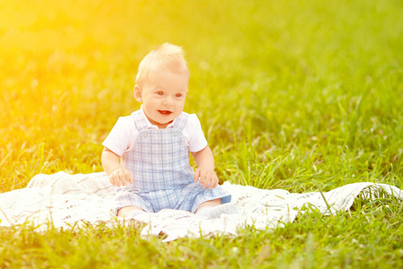 可爱的小宝宝在草地上的夏天公园里。 可爱的户外宝宝。 微笑