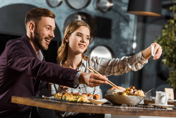 美丽的年轻夫妇在餐馆吃饭时自拍