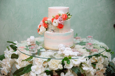 多层婚礼蛋糕装饰着鲜花站在桌子上。 在聚会上吃糖果和甜点的概念