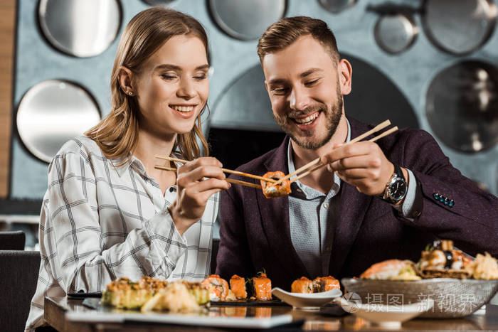 微笑，迷人的年轻夫妇一起在餐馆吃寿司