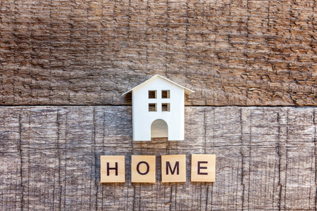 微型玩具模型房,在木制背景上刻有家字. 生态村抽象环境背景.
