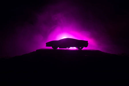 汽车在阴影中，在微光或轮廓的跑车黑暗背景下发光。 选择性聚焦