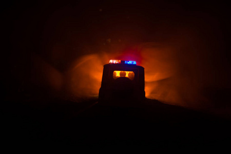 警车在晚上追逐一辆有雾背景的车。 911紧急反应警车超速到犯罪现场。 选择性聚焦