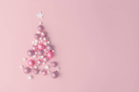 圣诞树由粉红色桌子背景上的球装饰制成。 顶部视图