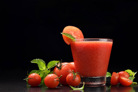 将番茄汁和切片番茄混合在杯中，黑色背景