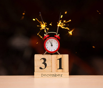 十二月三十一日在木制日历上,红色闹钟在黑暗模糊的背景上.