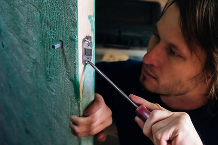 人安装内部木门门把手锁。 修理你的手。 这个人是个木匠大师。 用工具工作。