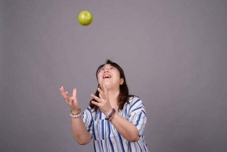 成熟的亚洲女商人捕捉绿色苹果的肖像