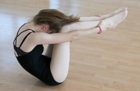 年轻的芭蕾舞演员在膝盖上工作。
