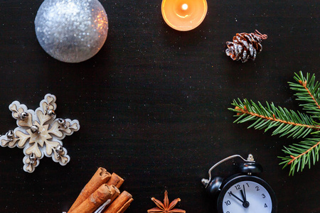 圣诞节新年作文冬季物体时钟蜡烛冷杉树枝鲍布和球在黑暗的黑色背景。 平躺顶部视图复制空间。 圣诞节十二月庆祝概念的时间